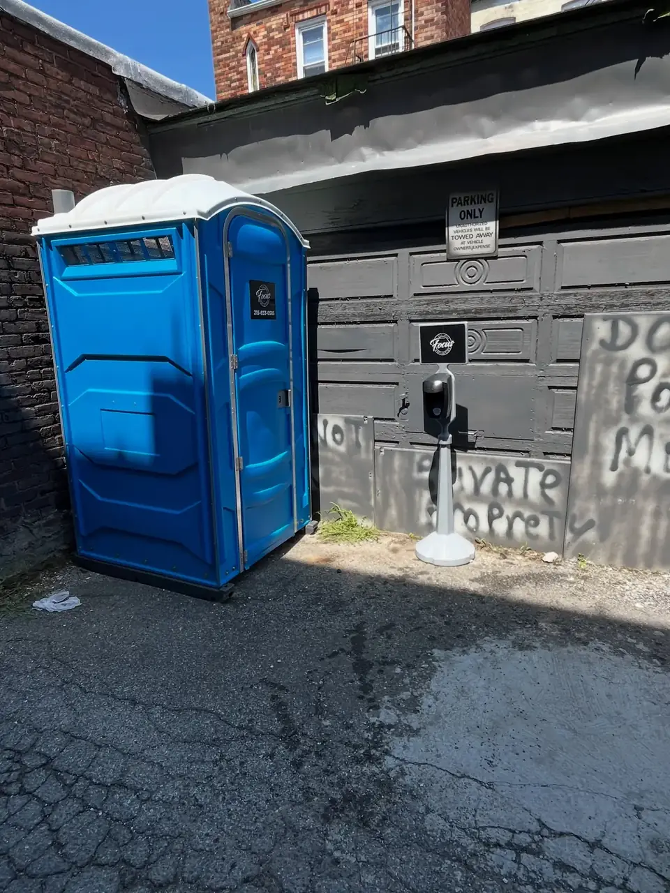 Blue porta potty beside a home driveway during a remodel